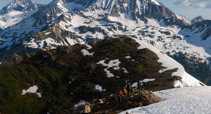 a group of outward bound students trek across a snowy mountainous landscape